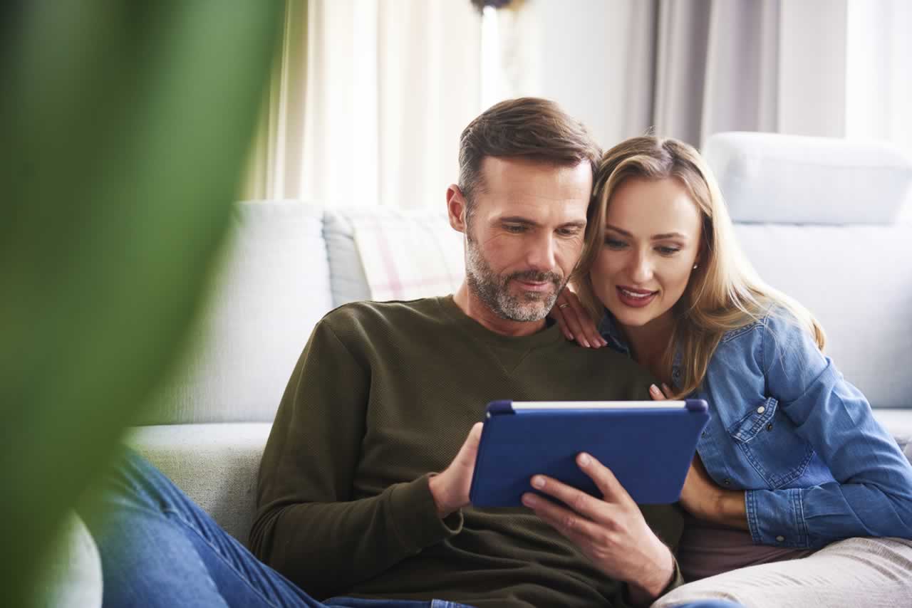 couple-using-a-tablet-in-living-room-2023-11-27-05-03-21-utc-m Reflecting on Your Journey: How to Create a Meaningful Vow Renewal Ceremony That Honors Your Milestone Anniversary